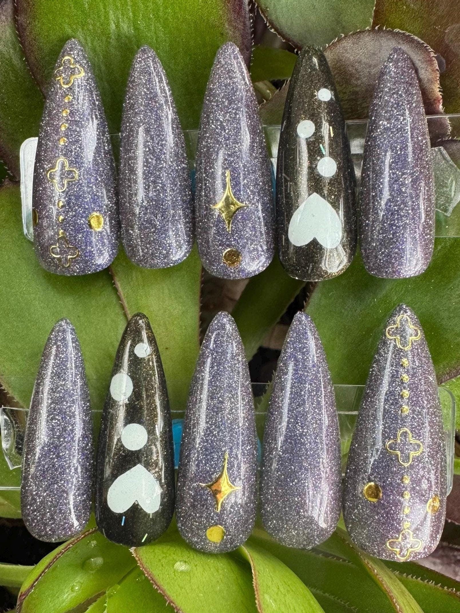 Set of decorative nails with various designs on a green leaf background
