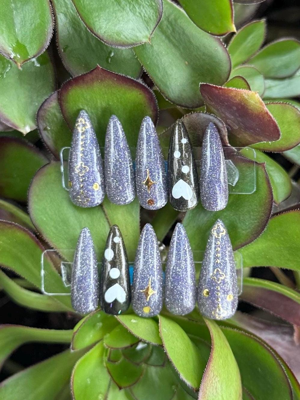Set of decorative nails on a clear stand with green leaves in the background